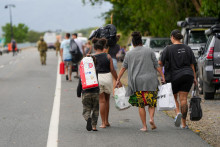 Obyvatelia mesta Cairns boli evakuovaní. Na fotografii kráčajú so svojimi vecami okolo miestnej pláže. FOTO: Reuters
