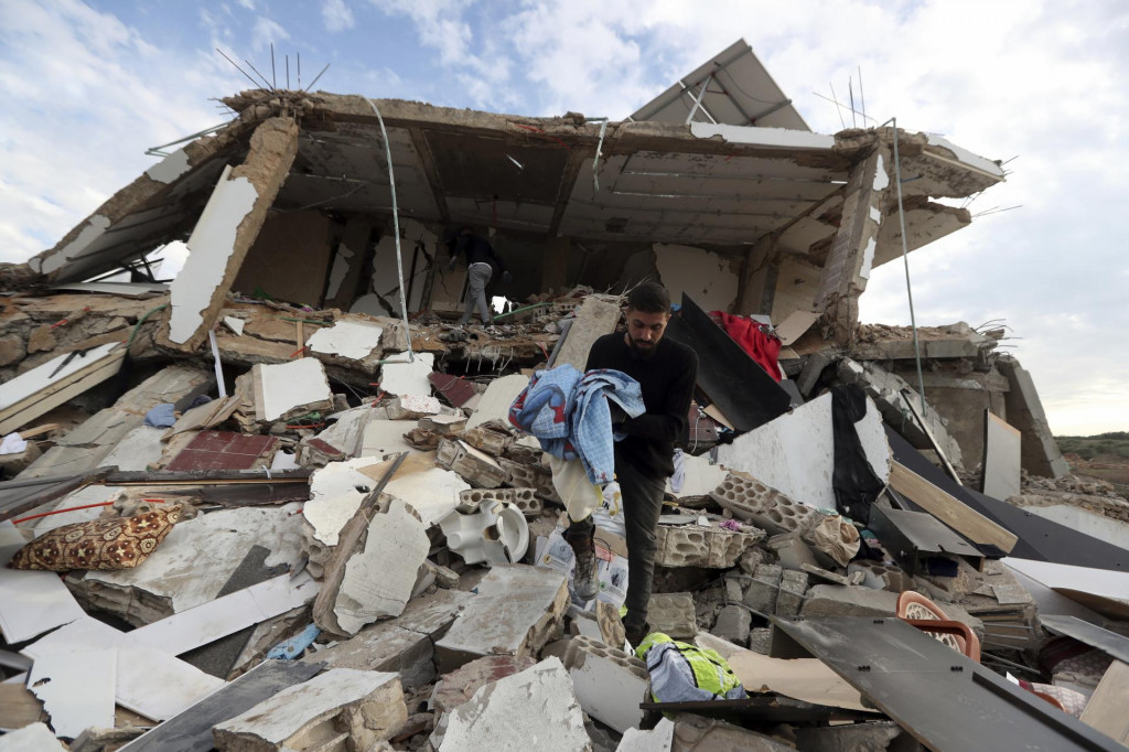 Muž si odnáša osobné veci zo zničeného domu, ktorý zasiahol nočný raketový útok izraelskej armády v dedine na juhu Libanonu. FOTO: TASR/AP