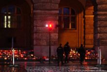 Policajti hliadkujú oblasť, kde ľudia kladú kvety a sviečky pred budovou Filozofickej fakulty Univerzity Karlovej po štvrtkovej masovej streľbe v centre Prahy. FOTO: TASR/AP