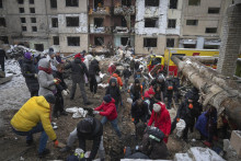 Dobrovoľníci a miestni obyvatelia zbierajú trosky z obytnej budovy, ktorú zasiahol ruský raketový útok v Kyjeve. FOTO: TASR/AP