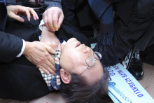 Líder juhokórejskej opozície I Če-mjong leží na zemi po útoku v juhokórejskom meste Pusan. FOTO: TASR/AP