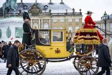 Dánska kráľovná Margaréta II., ktorú sprevádzajú príslušníci dánskeho husárskeho pluku, máva zo zlatého koča počas jazdy ulicami Kodane.