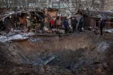 Miestni obyvatelia sa pozerajú na kráter v blízkosti svojej obytnej budovy poškodenej počas ruského raketového útoku.  FOTO: Reuters