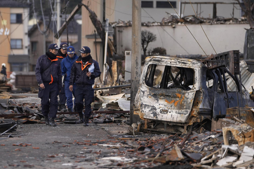 Hasiči prechádzajú okolo vrakov zhorených aút po požiari po ničivom zemetrasení v japonskom meste Wadžima 5. januára 2024.