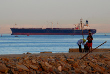 Ľudia chodia po pláži, keď kontajnerová loď pláva cez Suezský záliv smerom k Červenému moru pred vstupom do Suezského prieplavu. FOTO: Reuters