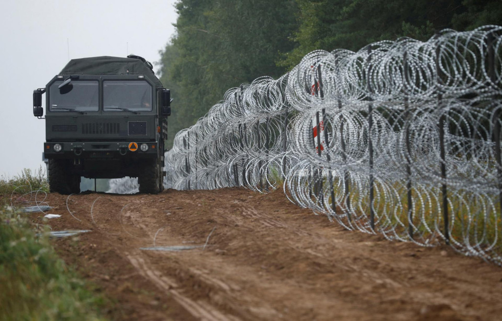 Vojenské vozidlo prechádza popri plote, ktorý postavili poľskí vojaci na hranici medzi Poľskom a Bieloruskom. FOTO: Reuters