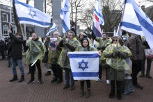 Demonštranti džia izraelské, holandské vlajky a fotografie Hamasom unesených osôb zo 7. októbra 2023 pred budovou Medzinárodného súdneho dvora v holandskom Haagu. FOTO: TASR/AP
