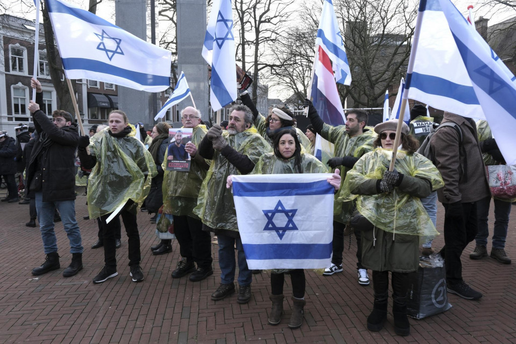 Demonštranti džia izraelské, holandské vlajky a fotografie Hamasom unesených osôb zo 7. októbra 2023 pred budovou Medzinárodného súdneho dvora v holandskom Haagu. FOTO: TASR/AP