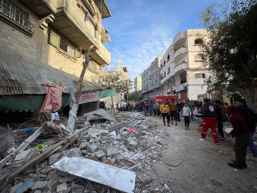 Palestínčania stoja pred poškodenou budovou na mieste izraelského úderu v utečeneckom tábore Maghazi v centrálnom pásme Gazy. FOTO: Reuters