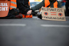 Climate change activists of Letzte Generation (Last Generation) block a road holding a placard reading ”climate crisis = food crisis”, the same time as German farmers protest all over the country against the cut of the farm vehicle tax subsidies in Berlin, Germany, January 10, 2024. REUTERS/Liesa Johannssen FOTO: Liesa Johannssen