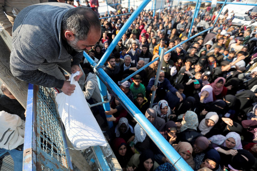 Palestínsky muž drží vrece s múkou, zatiaľ čo ostatní čakajú, kým dostanú to svoje vrecia od Agentúry OSN pre pomoc a prácu. FOTO: Reuters
