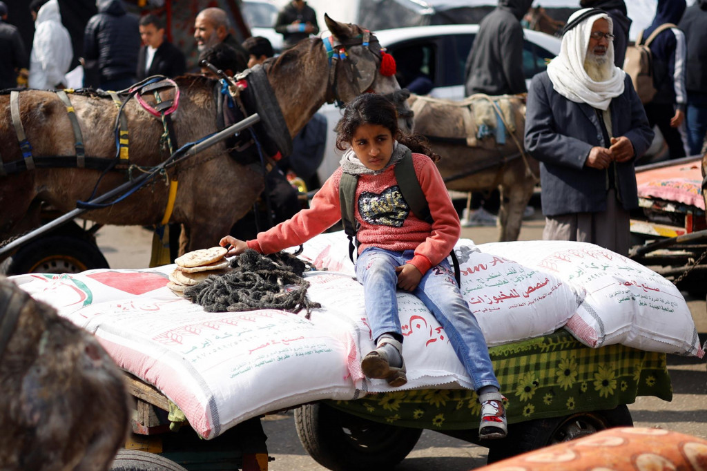Palestínske dievča sedí na vreciach s múkou, ktoré distribuuje Agentúra OSN pre pomoc a prácu. FOTO: Reuters