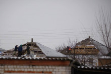 Robotníci opravujú strechu poškodeného domu v obci Petropavlovka, ktorý deň predtým náhodne zbombardovalo jedno z ruských vojenských lietadiel. FOTO: Reuters