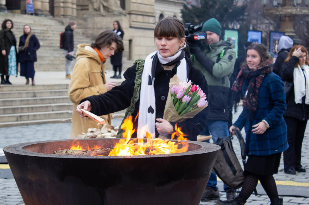 Dievča prikladá polienko do pietneho ohňa za obete streľby na Filozofickej fakulte Univerzity Karlovej v Prahe. FOTO: TASR/Barbora Vizváryová