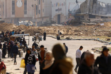 Palestínčania utekajú smerom k Rafahu, kráčajúc popri izraelských vojenských vozidlách. FOTO: Reuters