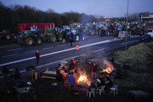 Francúzski poľnohospodári sa zohrievajú pri ohni po strávení noci na diaľnici v Ourdy, južne od Paríža. FOTO: TASR/AP