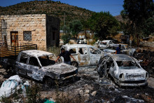 Palestínčania kontrolujú spálené vozidlá po útoku izraelských osadníkov. FOTO: Reuters