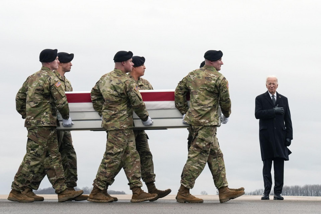Americký prezident Joe Biden (vpravo) stojí, zatiaľčo príslušníci americkej armády vynášajú rakvu s telesnými pozostatkami amerického vojaka, seržanta Kennedyho Ladona Sandersa, ktorý zahynul pri útoku dronom na vojenskej základni známej ako Tower 22 na severovýchode Jordánska. FOTO: TASR/AP
