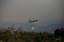 Helikoptéra letiaca nad spálenou oblasťou púšťa vodu počas šírenia lesných požiarov v Čile. FOTO: Reuters