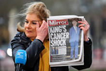 Žurnalistka drží výtlačok novín Daily Mirror so správou o tom, že Karolovi III. bola diagnostikovaná rakovina. FOTO: Reuters