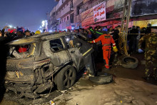 Príslušníci civilnej obrany zasahujú pri zhorenom aute po americkom dronovom útoku v Bagdade. FOTO: TASR/AP
