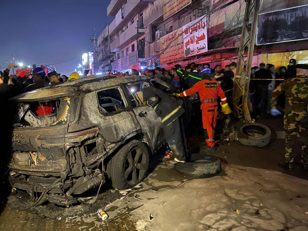 Príslušníci civilnej obrany zasahujú pri zhorenom aute po americkom dronovom útoku v Bagdade. FOTO: TASR/AP