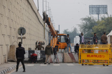 Policajti a robotníci stavajú barikádu na štátnej diaľnici, aby zastavili farmárov, ktorí na protest pochodujú smerom k Naí Dillí. FOTO: Reuters