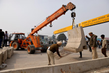 Policajti a robotníci stavajú barikády na národnej diaľnici, aby zastavili farmárov, ktorí pochodujú smerom k Naí Dillí. FOTO: Reuters
