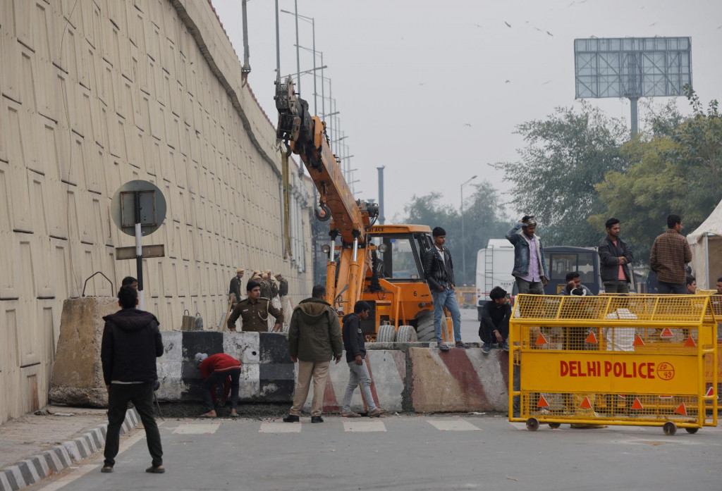 Policajti a robotníci stavajú barikádu na štátnej diaľnici, aby zastavili farmárov, ktorí na protest pochodujú smerom k Naí Dillí. FOTO: Reuters