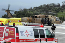 Izraelskí predstavitelia evakuujú osobu po pristátí rakety, ktorá bola odpálená z Libanonu. FOTO: Reuters