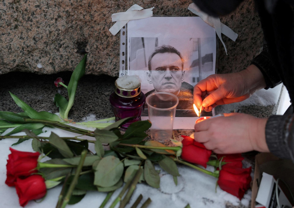 Rusi zapalujú sviečky a prinášajú kvety vedľa portrétu ruského opozičného vodcu Alexeja Navaľného pri pamätníku obetiam politických represií po Navaľného smrti v Petrohrade. FOTO: Reuters