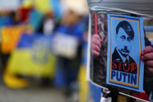Demonštrant drží plagát zobrazujúci ruského prezidenta Vladimira Putina ako Adolfa Hitlera. FOTO: Reuters