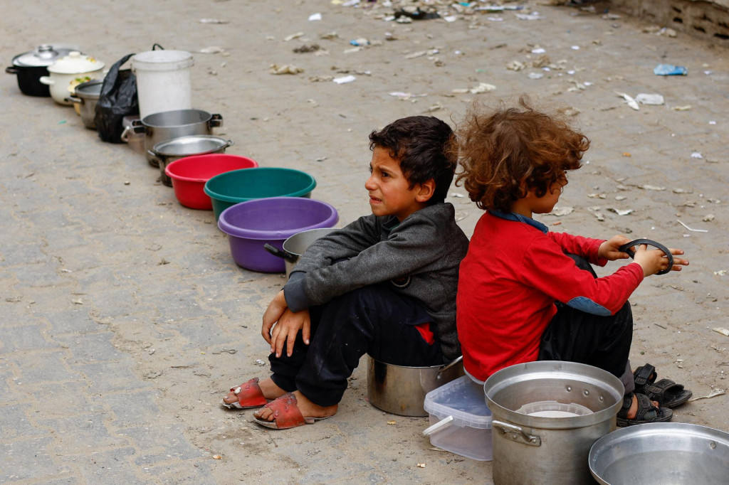 Palestínske deti čakajú, kým dostanú jedlo uvarené v charitatívnej kuchyni v Rafahu v južnom pásme Gazy. FOTO: Reuters