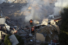 Palestínski záchranári hľadajú preživších v troskách zničenej obytnej budovy po izraelskom bombardovaní pásma Gazy. FOTO: TASR/AP