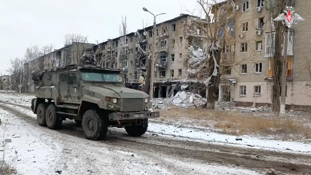 Ruské vojenské vozidlo jazdí popri obytných budovách poškodených v meste Avdjivka. FOTO: Reuters