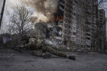 Na archívnej snímke ukrajinský vojak sa ukrýva pred horiacou obytnou budovou v meste Avdijivka. FOTO: TASR/AP