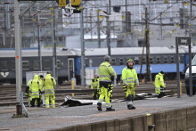 Zamestnanci premiestňujú časť strechy, ktorú strhol silný vietor na železničnej stanici v Göteborgu. FOTO: TASR/AP