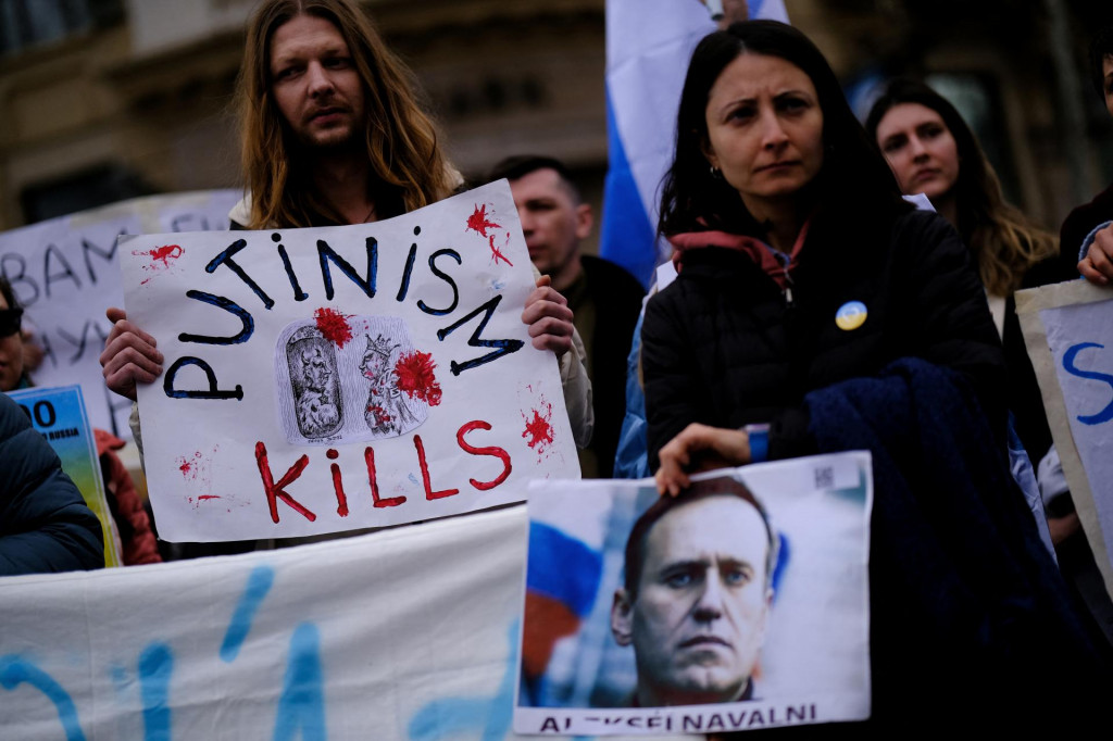 Ľudia držia transparent a obraz zosnulého ruského opozičného vodcu Alexeja Navaľného. FOTO: Reuters