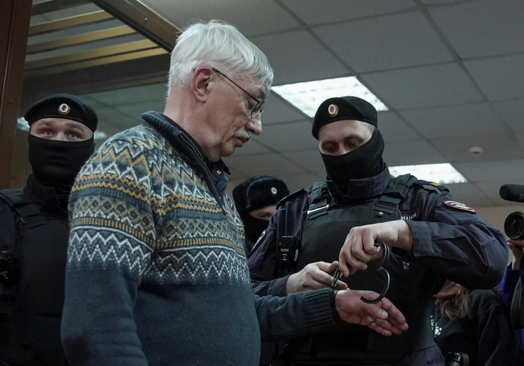 Policajt nasadil putá ruskému veteránovi, bojovníkovi za ľudské práva Olegovi Orlovovi počas súdneho pojednávania v Moskve. FOTO: Reuters