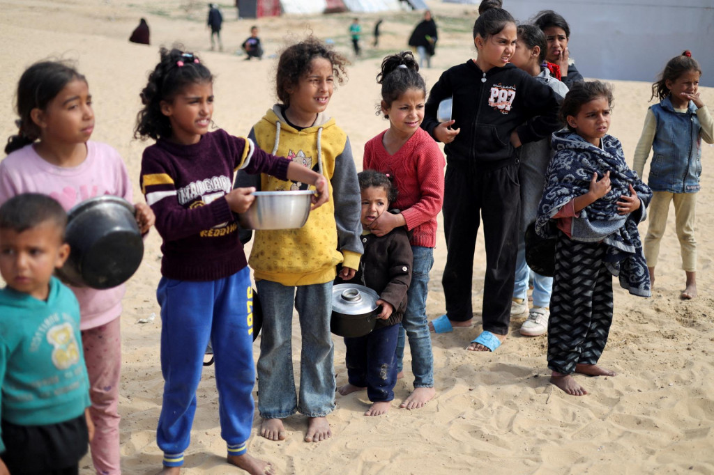 Vysídlené palestínske deti čakajú na bezplatné jedlo v stanovom tábore. FOTO: Reuters