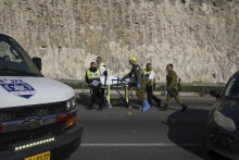 Prílsušníci izraelských bezpečnostných síl a záchranári Zaka vynášajú telo z miesta streľby. FOTO: TASR/AP