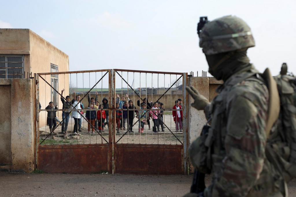 Vojak koalície vedenej USA ukazuje smerom k školákom počas spoločnej hliadky Sýrskych demokratických síl pod vedením USA a Kurdov na severovýchode Sýrie. FOTO: Reuters