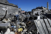 Palestínčania prehľadávajú trosky zničených obytných budov. FOTO: TASR/AP