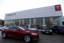 Auto Tesla prechádza okolo obchodu výrobcu elektrických vozidiel  v Pekingu. FOTO: Reuters