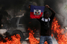 Demonštrant dvíha haitskú vlajku počas protestu proti vláde a neistote premiéra Ariela Henryho v Port-au-Prince. FOTO: Reuters