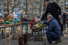 Ľudia zapaľujú sviečky a kladú kvety k provizórnemu pamätníku obetiam predošlého náletu bezpilotného lietadla, ktorý ťažko poškodil bytový dom v Odese. FOTO: Reuters