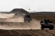 Vojenské vozidlá manévrujú pri hraničnom plote medzi Izraelom a Gazou. FOTO: Reuters