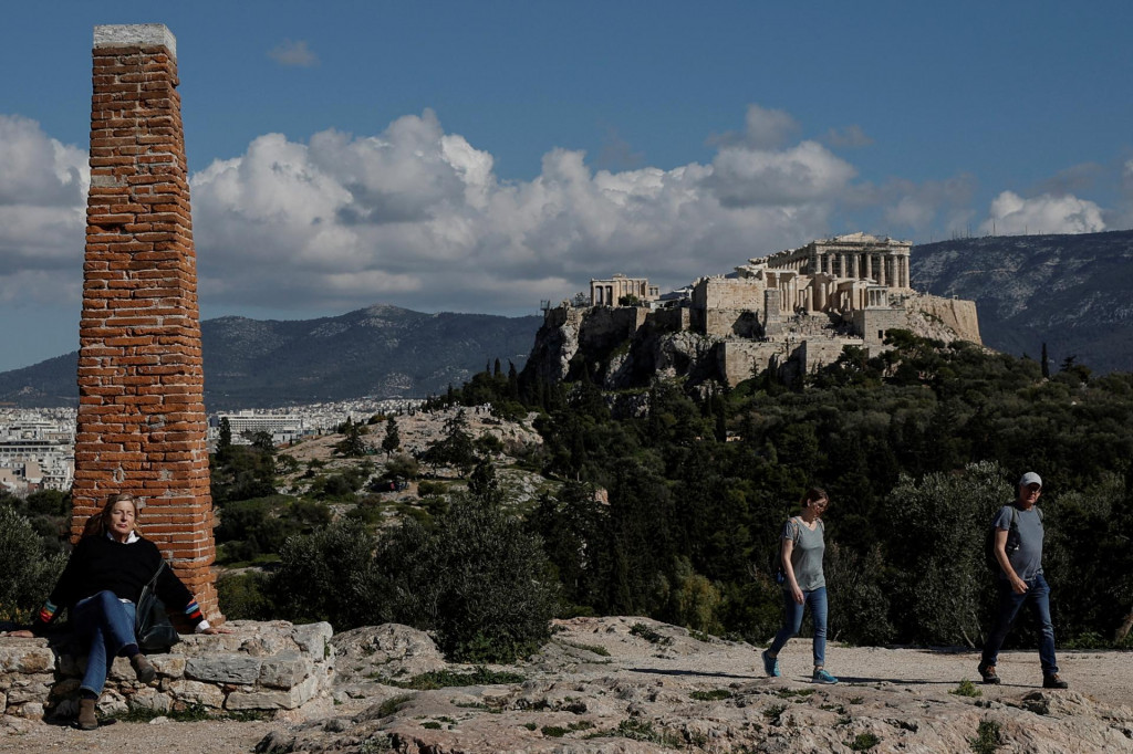 Ľudia si užívajú teplý deň na kopci Pnyx pri Akropole v Aténach. FOTO: Reuters