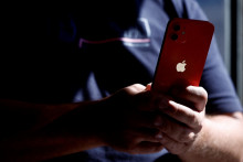 Osoba na snímke drží smartfón Apple iPhone 12. FOTO: REUTERS