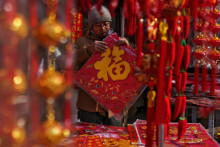 Muž si vyberá novoročné dekorácie na trhu v Pekingu pred oslavami čínskeho lunárneho nového roka. Nový lunárny rok, rok Dreveného draka, sa oficiálne začal v nedeľu 10. februára. FOTO: TASR/AP